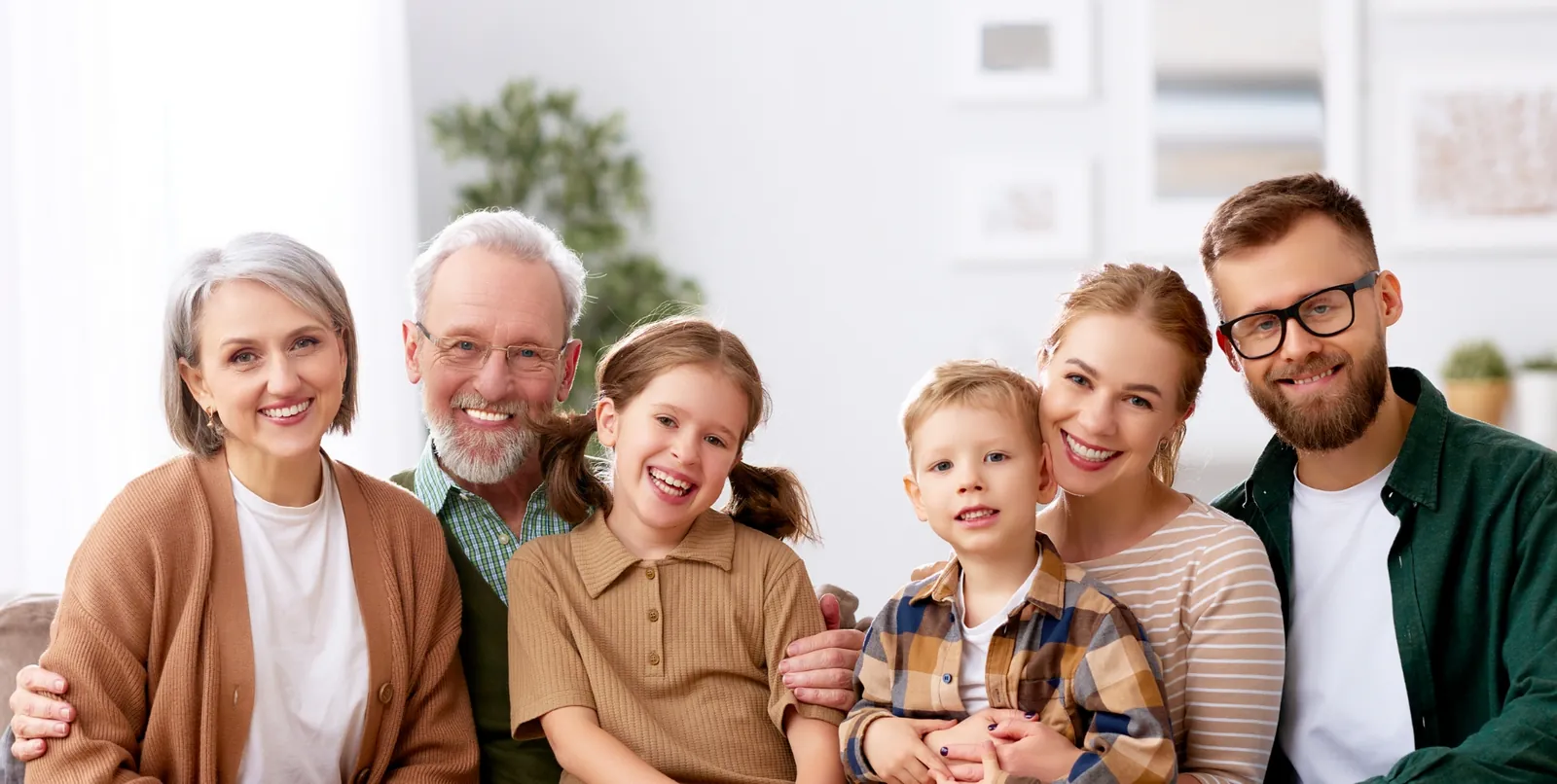 Three generations of a smiling family sitting together at home